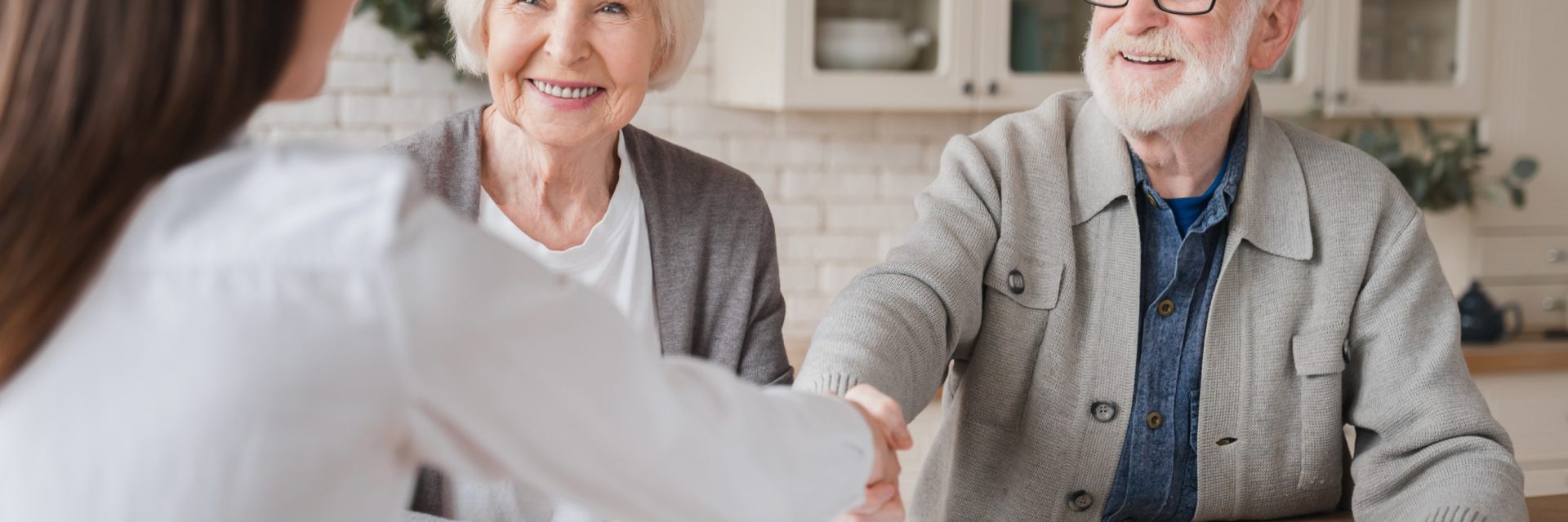 Deux personnes agées signent un contrat avec un employé de bureau