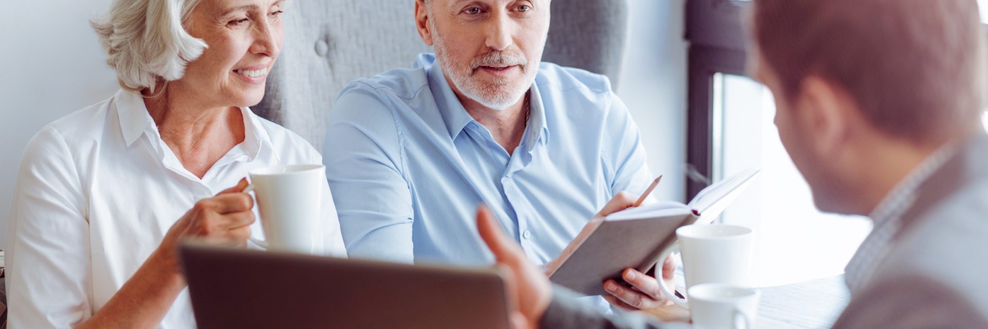 Un couple âgé souriant consulte un agent d'assurance